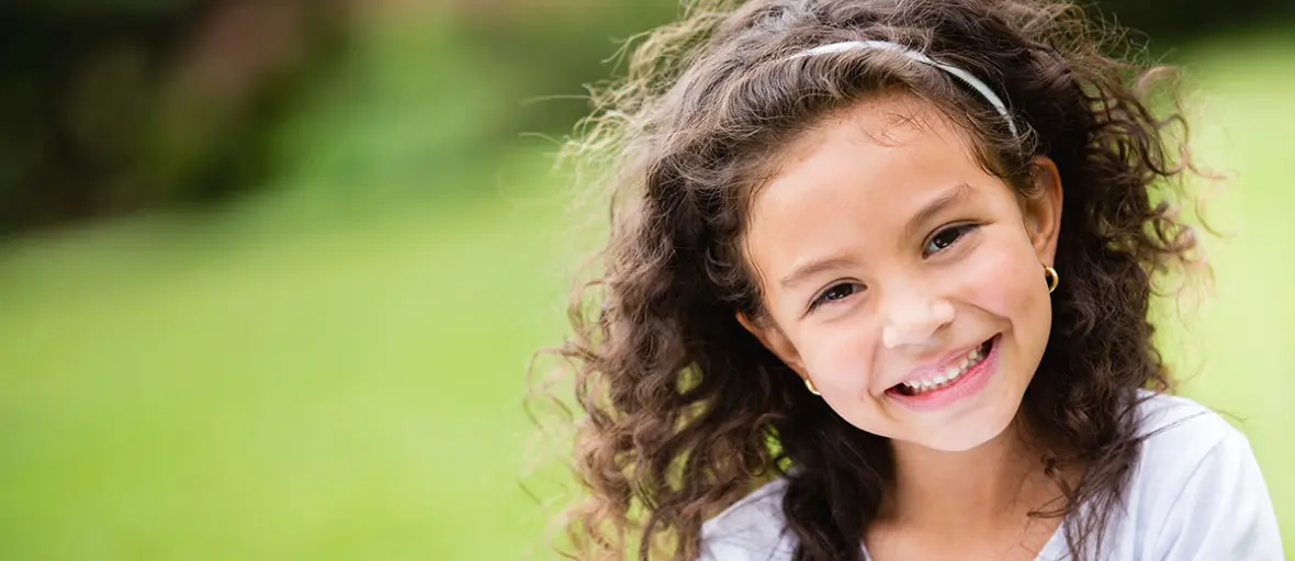 A young girl with long hair smiles for the camera.